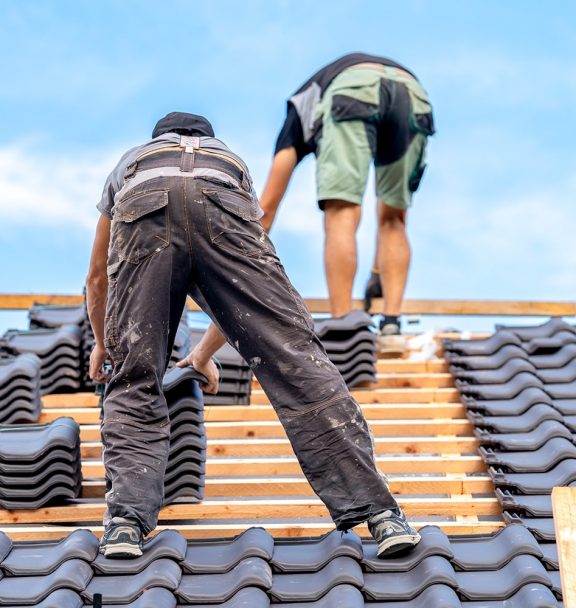 craftsmen-build-new-roof-from-ceramic-tiles-wooden-beams-min